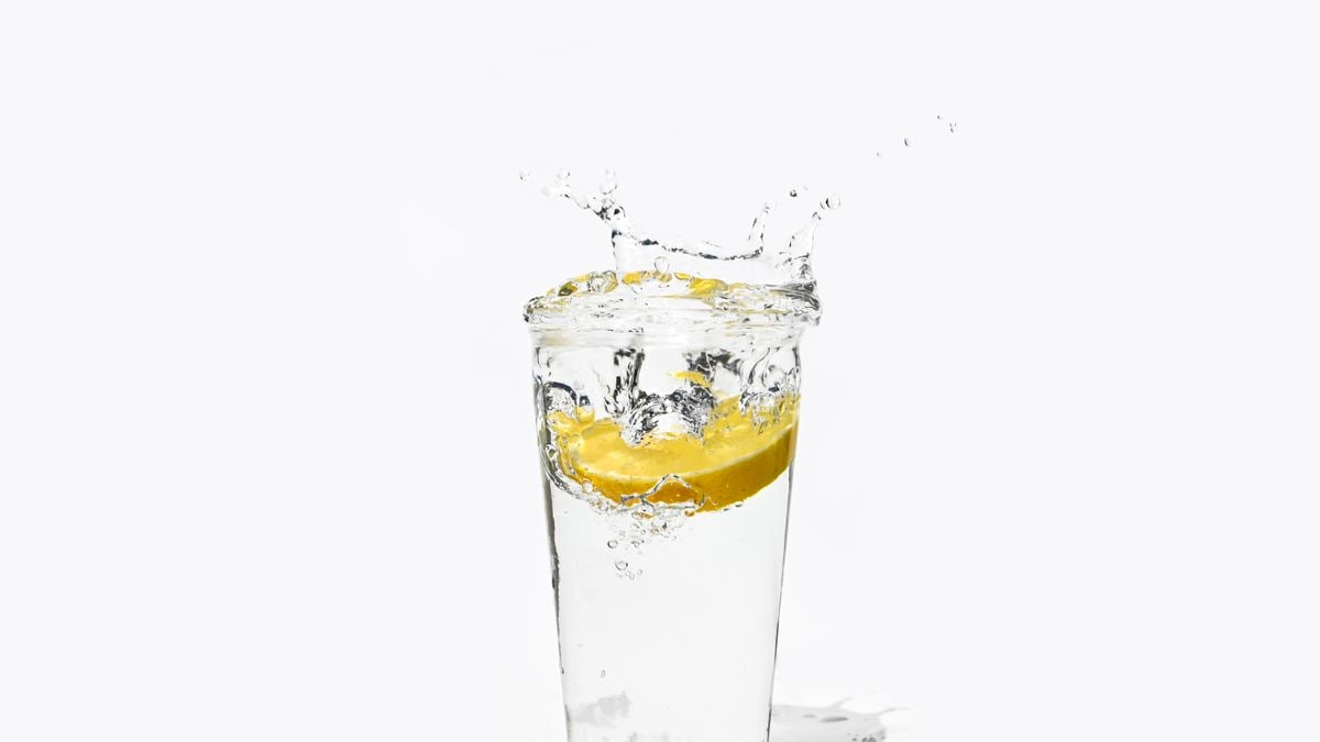 A vibrant splash of water with a lemon slice in a glass, perfect for refreshment concepts.
