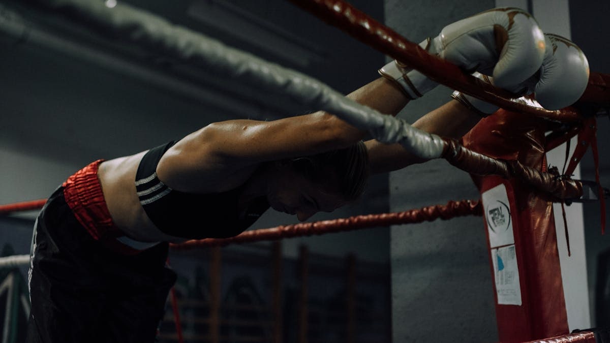 A dedicated female boxer rests in the ring, showcasing strength and perseverance.